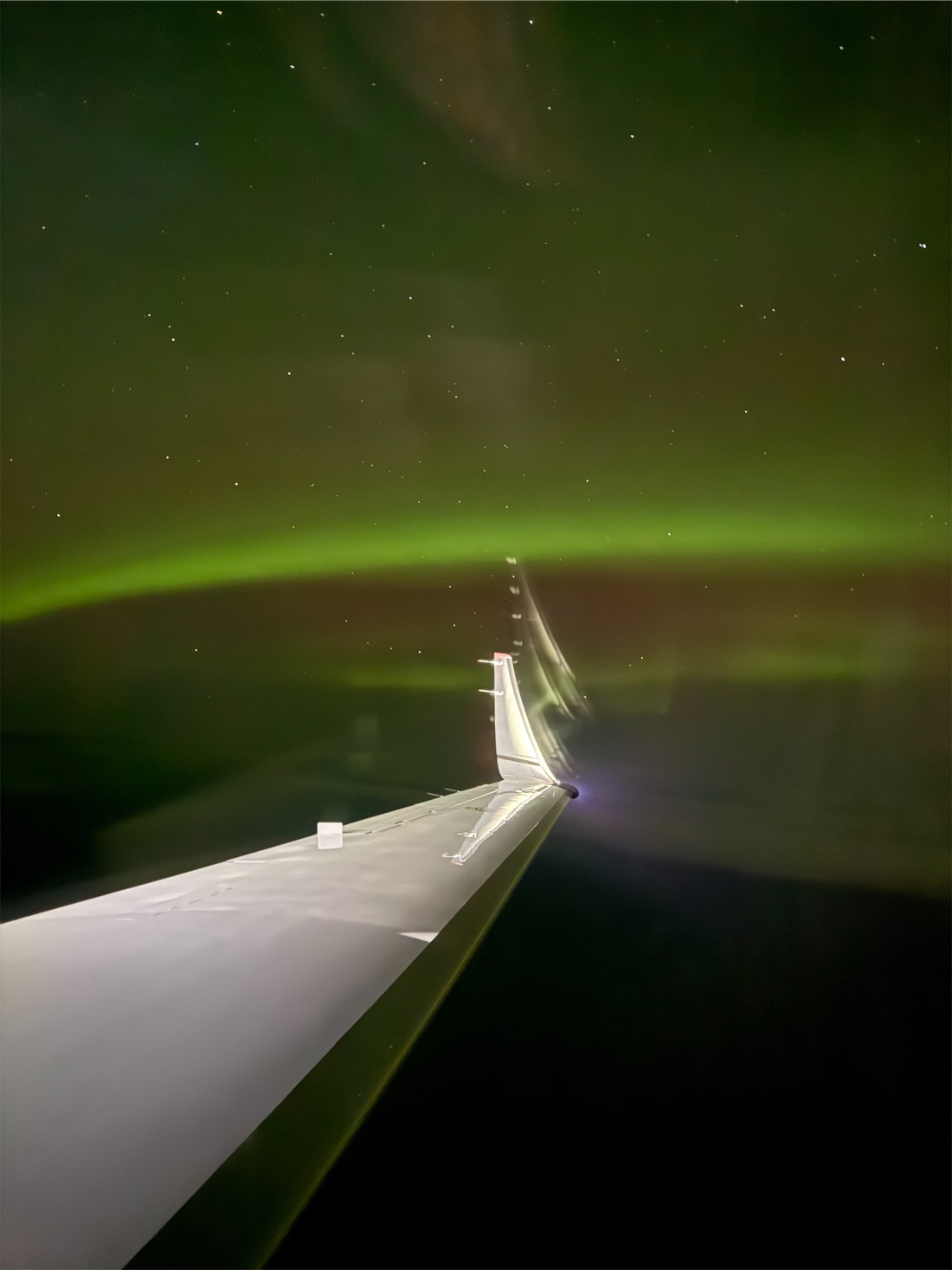 Northern lights over the wing of a business jet at night